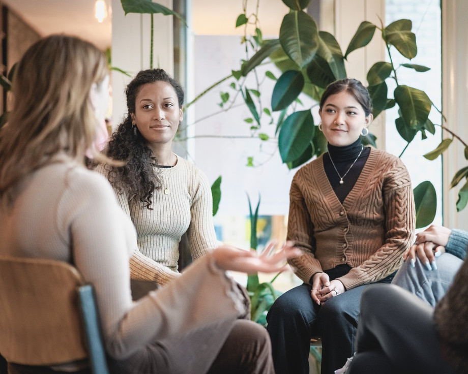 Vier Personen sitzen in einem Kreis und unterhalten sich.