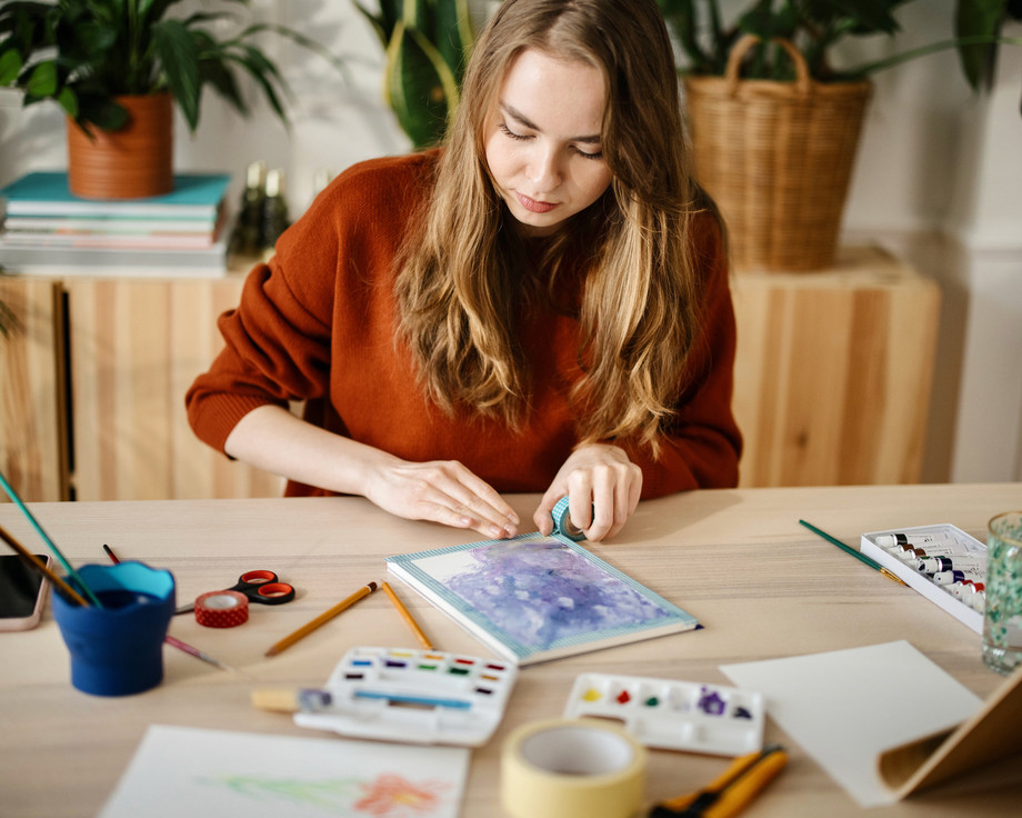 Eine Frau malt mit Wasserfarben an einem Tisch.