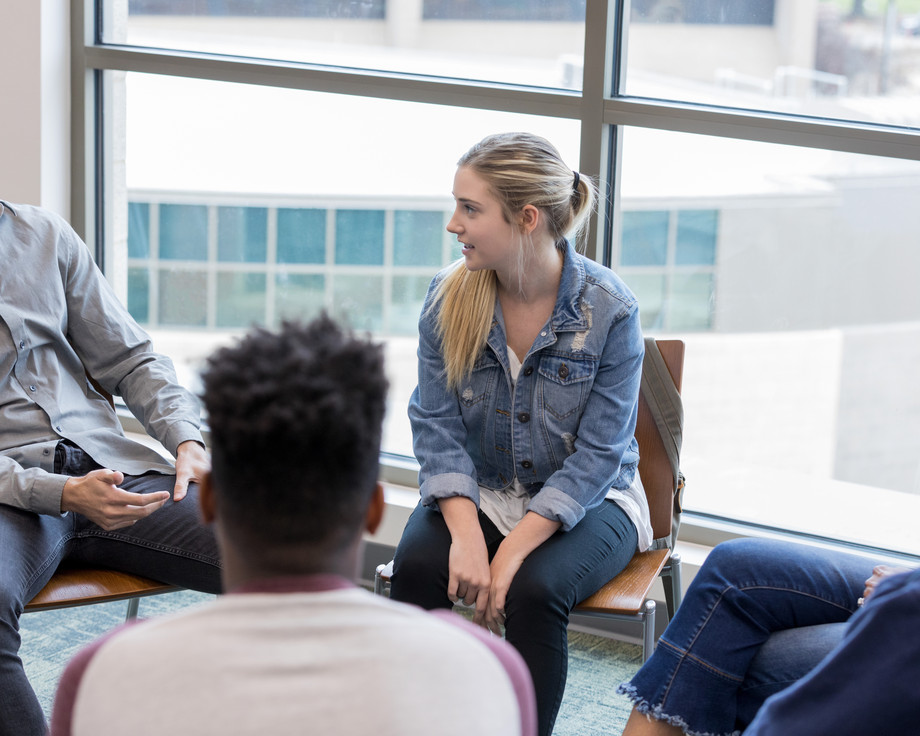 Eine Gruppe von Menschen sitzt in einem Kreis und diskutiert.