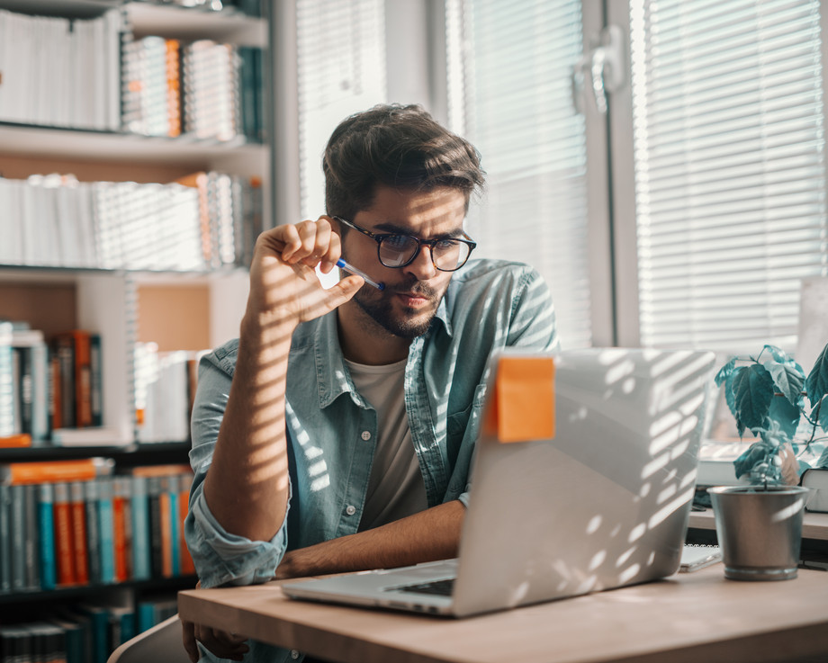Ein Mann sitzt an einem Schreibtisch und arbeitet an einem Laptop.